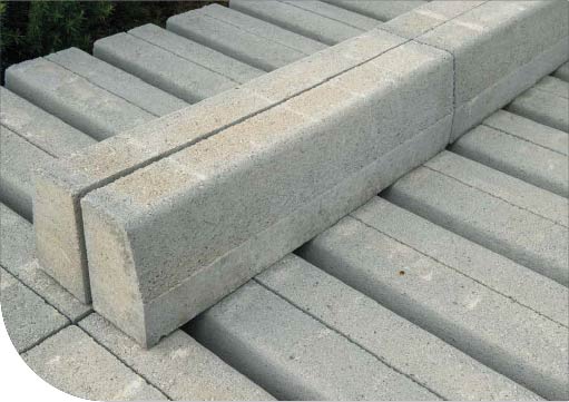 Blocs de béton rectangulaires gris empilés perpendiculairement, montrant des lignes nettes et une surface lisse, utilisés pour la construction ou l'aménagement extérieur.